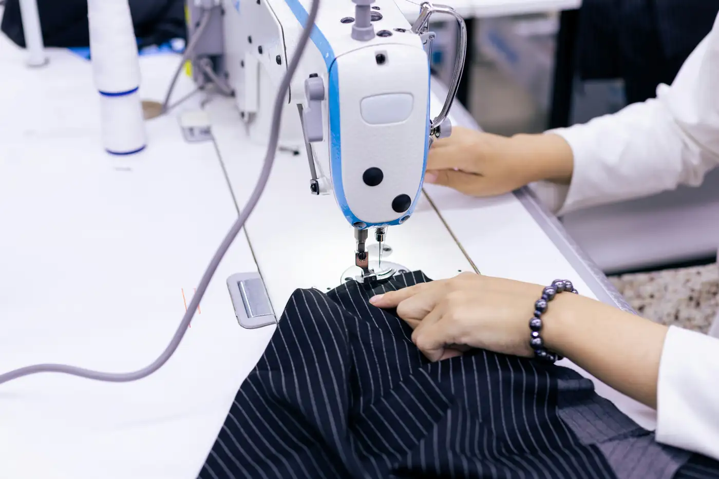 Hands sewing a garment on a sewing machine